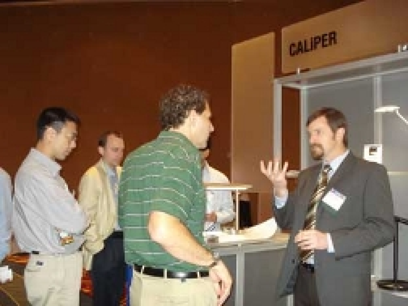 A photo of an attendee questioning a speaker about lighting fixtures on display.