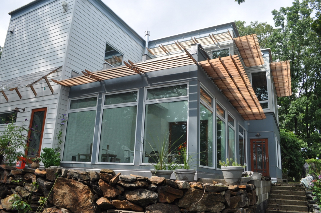 Photo of the exterior of a house, showing a glassed-in patio in the forefront.