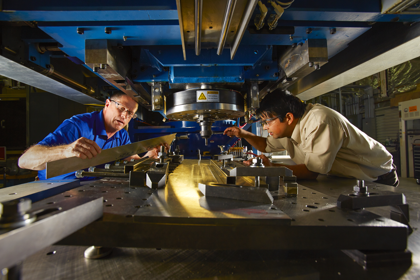 Two men engaged in friction stir welding.