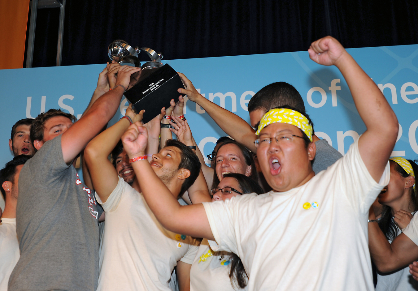 Solar Decathlon winners cheer and hold up a trophy.