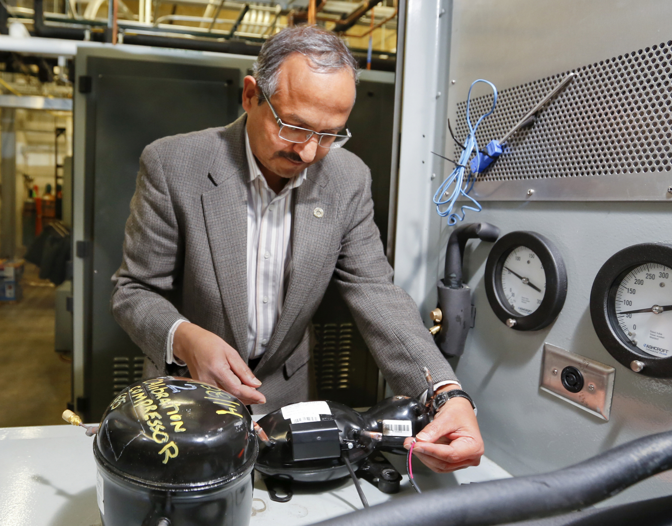 ORNL’s Pradeep Bansal examines an Embraco linear compressor.