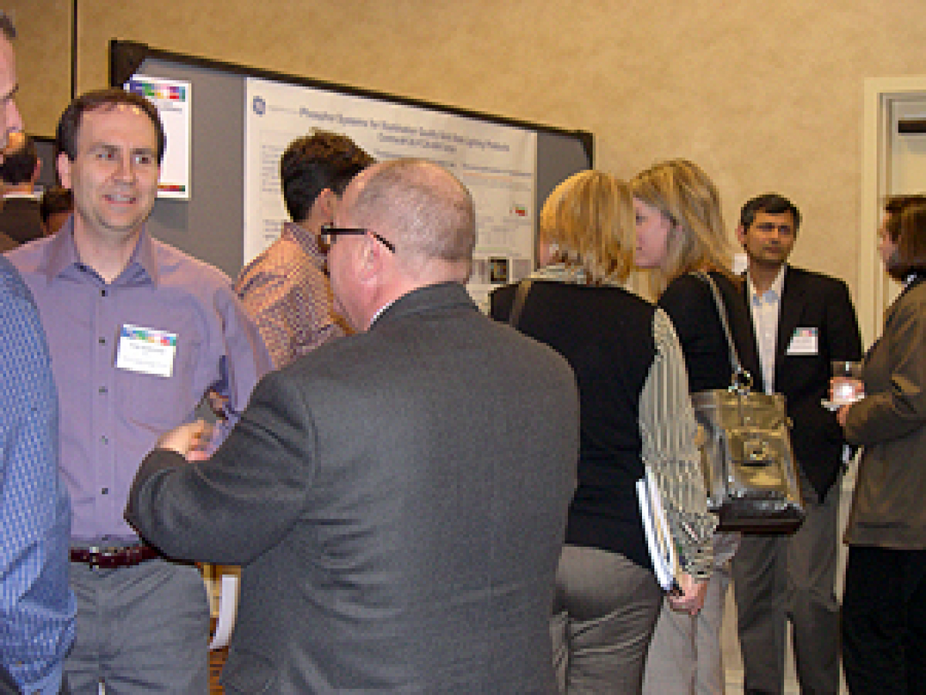 Photo of a group of people standing and talking to each other in an exhibit hall.