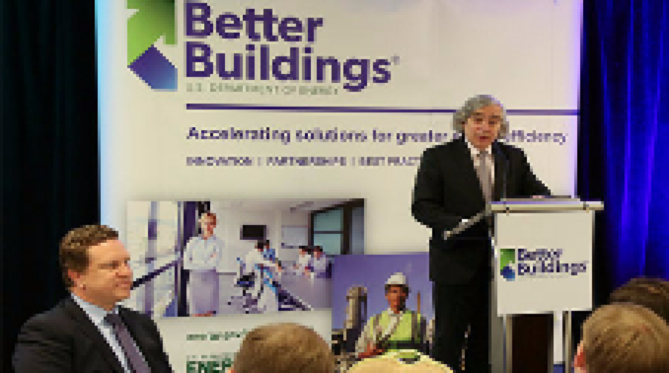 The former Secretary of Energy speaking at a podium with a backdrop of the Better Buildings program.