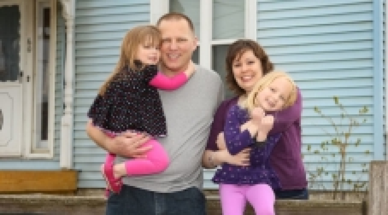 Photo of a family standing in front of a house.