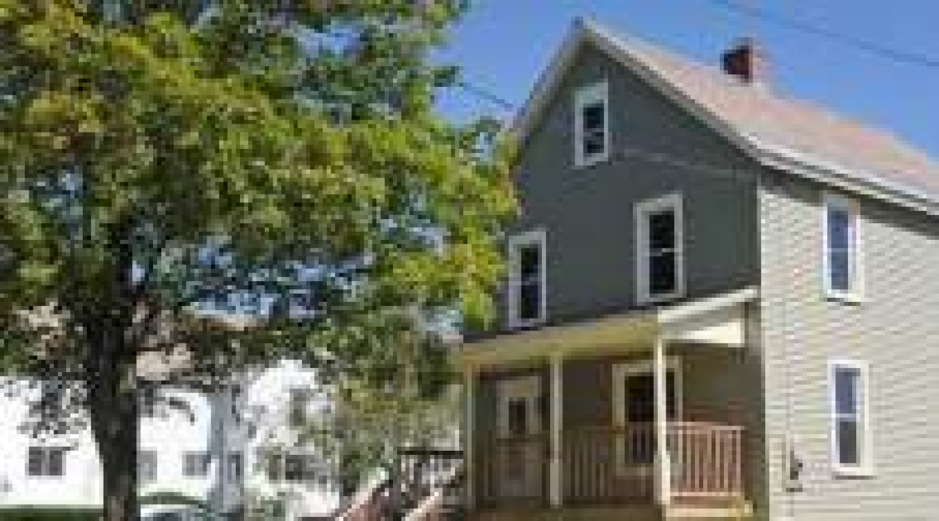 Photo of the outside of a two-story house, with a tree nearby.