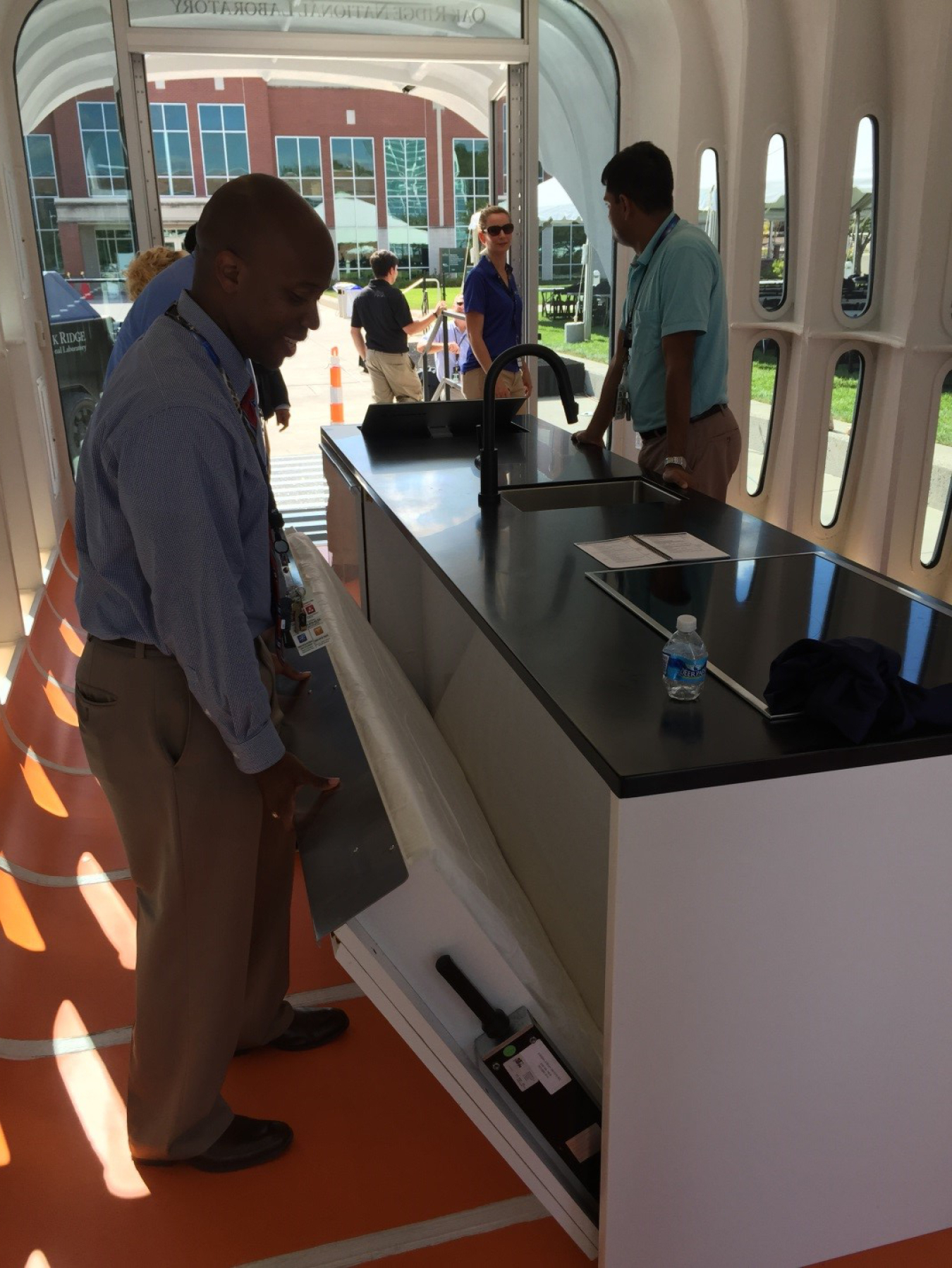 Photo of Industry Day MVP Rodrick Jackson showing us GE’s micro-kitchen, designed and manufactured for AMIE complete with stove, dishwasher, microwave, refrigerator, sink, and bed.