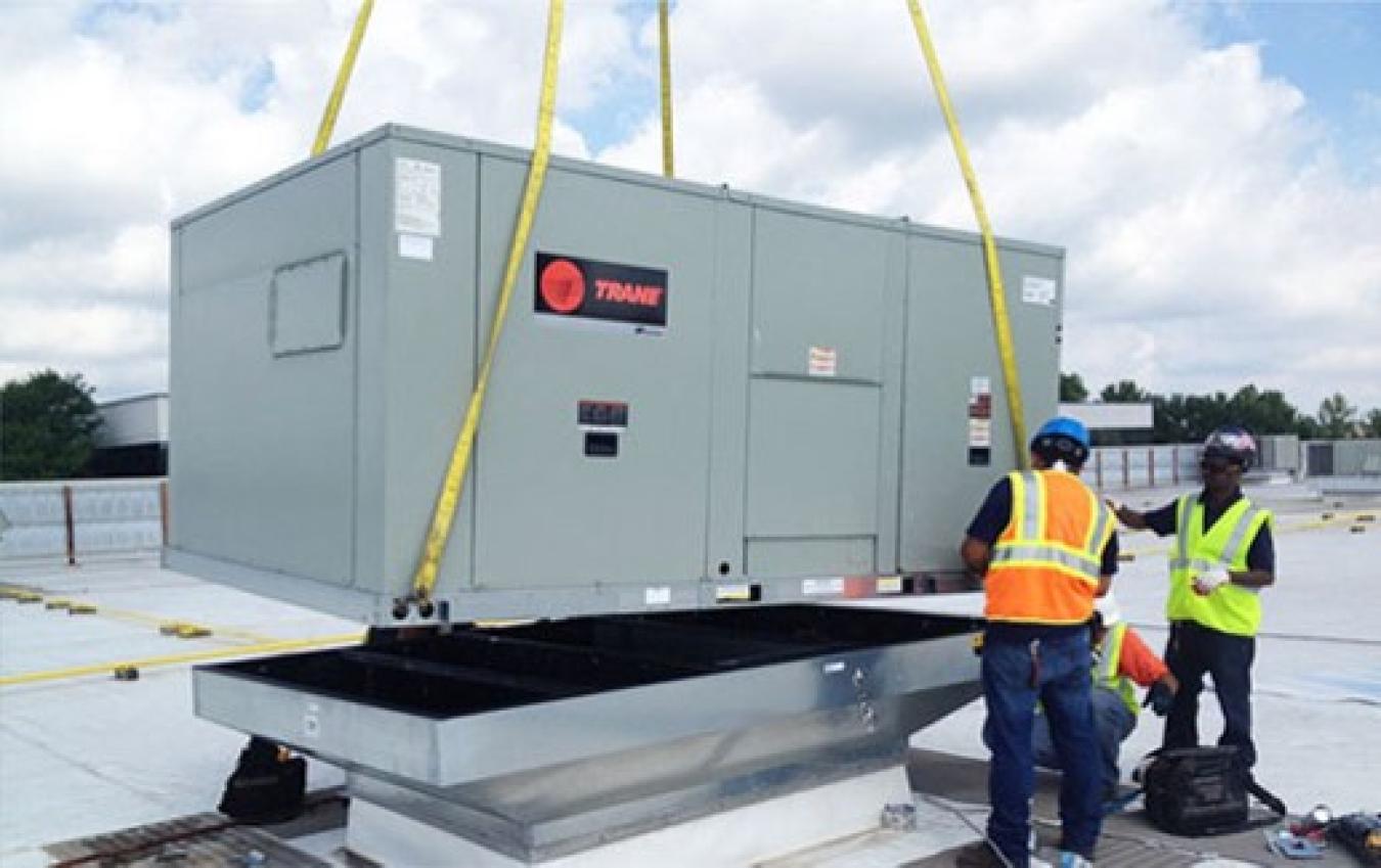 Two people standing near a commercial rooftop air-conditioning unit (RTU).