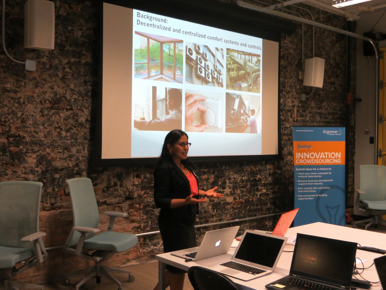 Woman making a presentation to a group, with a projection screen on the wall behind her.