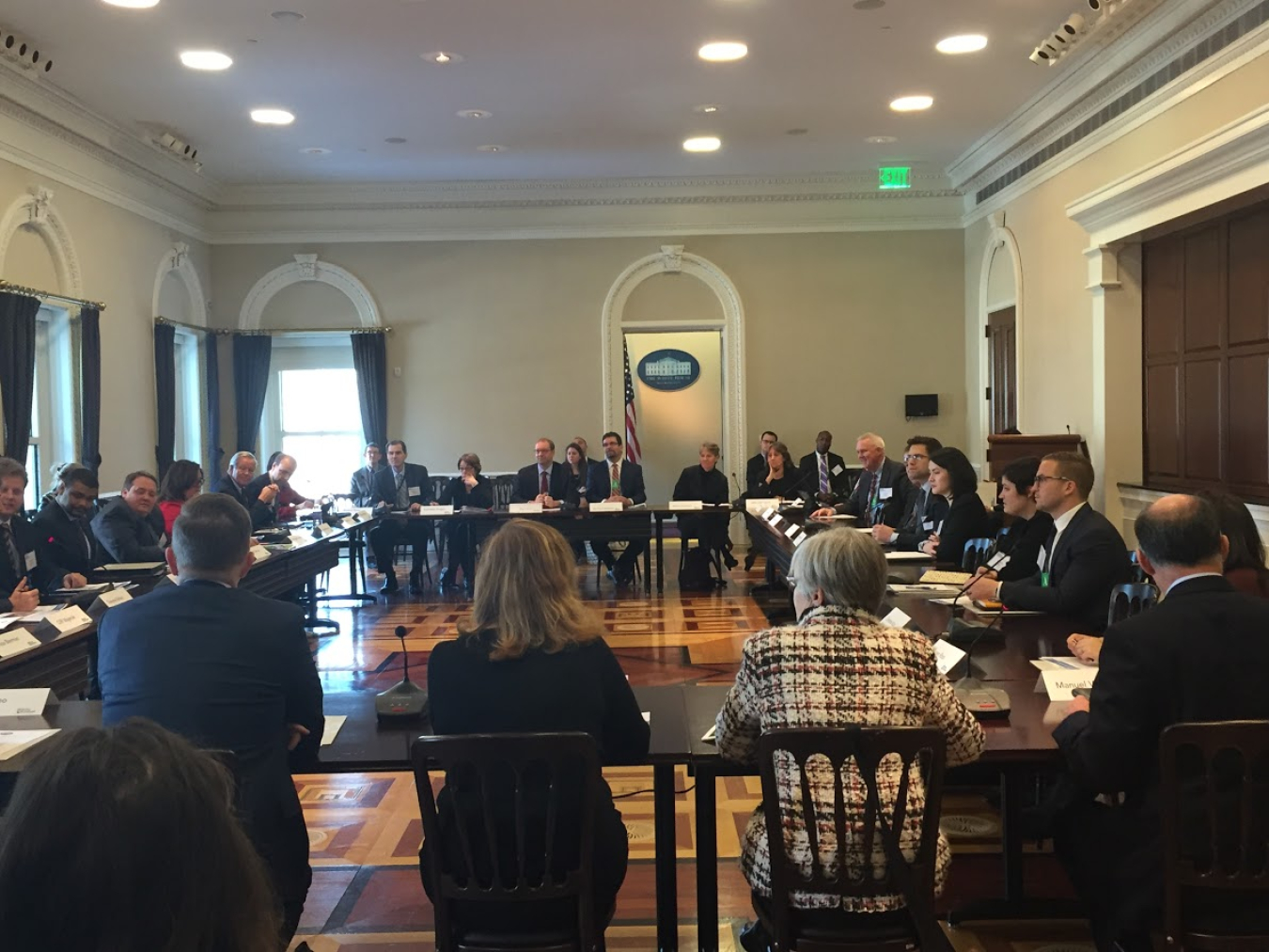 Group of people seated around a table in a meeting room.