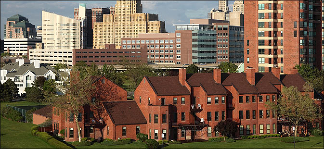 Photo of a city skyline of office buildings, with an apartment complex in the foreground.