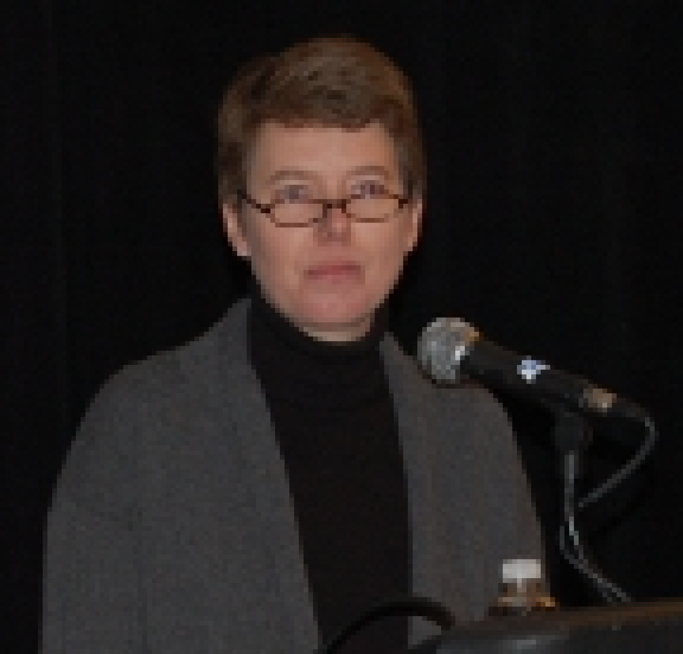 Photo of a woman standing in front of a microphone.