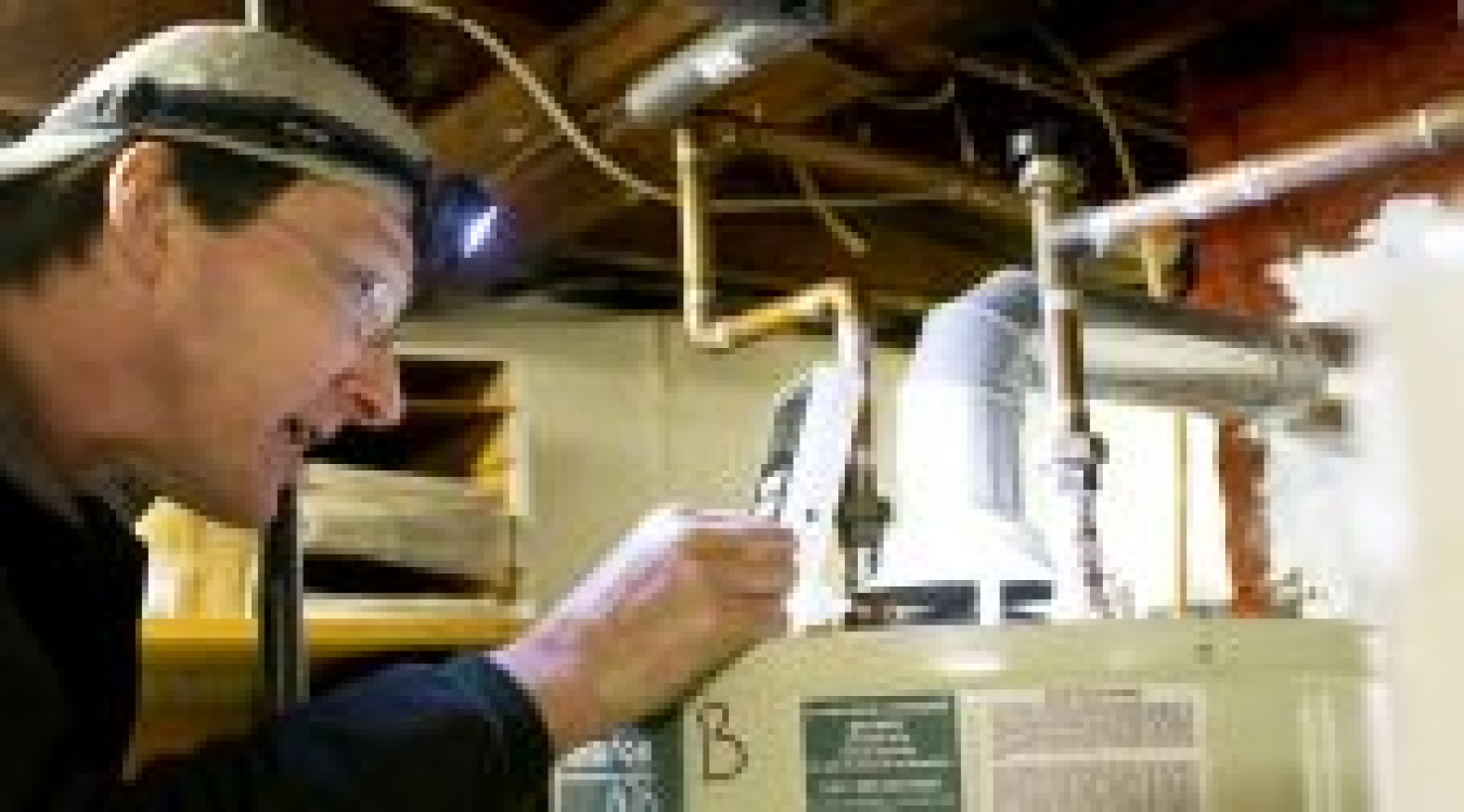 A man examining a hot water heater.