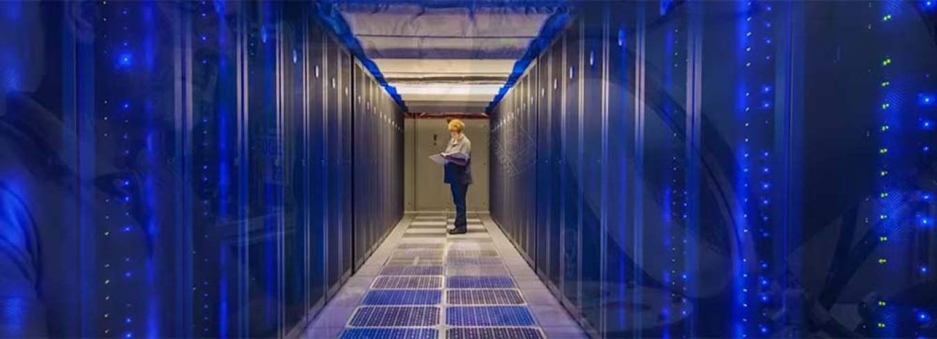 A photo of a person standing at the far end of a row of computer servers. 