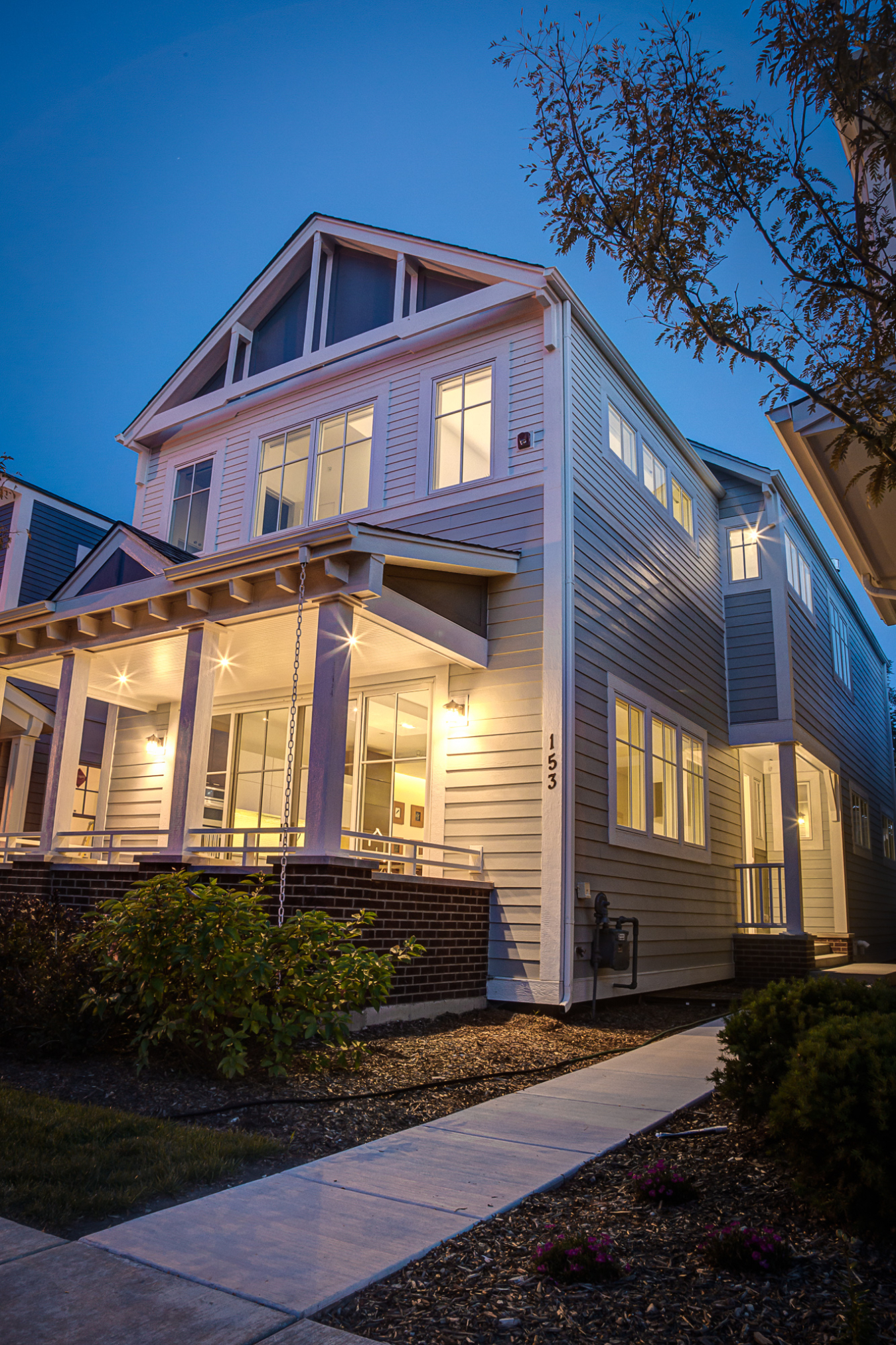 Photo of a two-story home lit up from within against a dark sky.