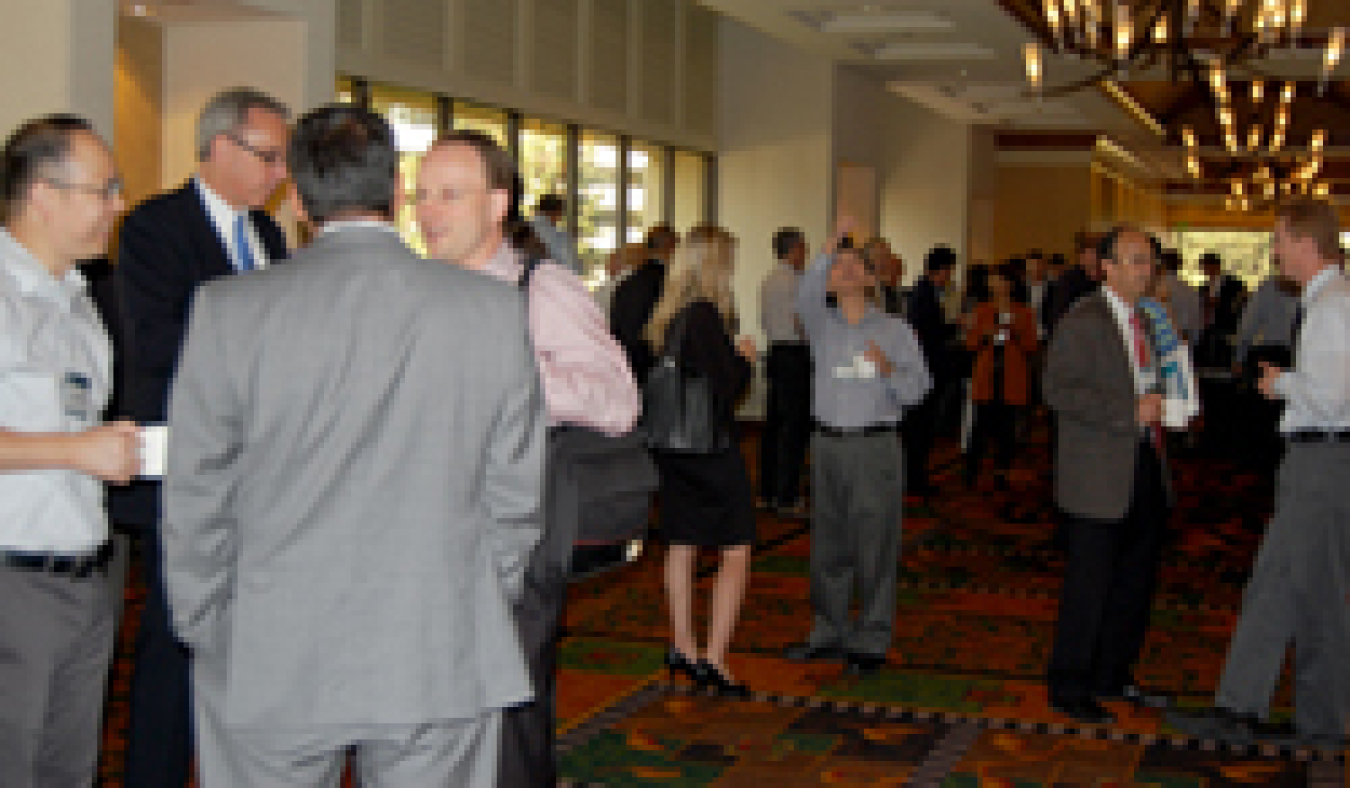 Photo of small groups of people standing in a hallway, talking to each other.