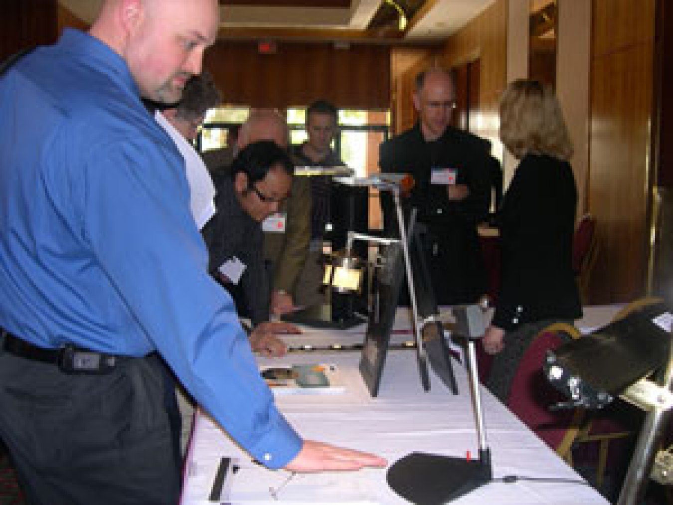Photo of a group of people looking at table lamps displayed on a long table.