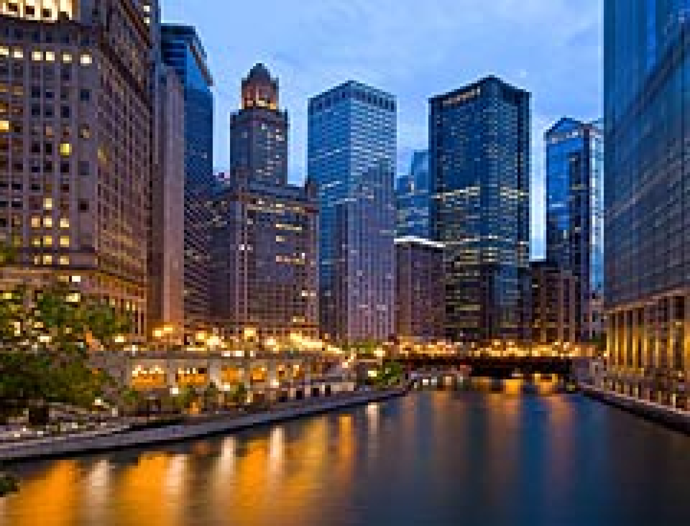 Photo of a city's downtown, with lots of tall office buildings, and a river in the foreground.