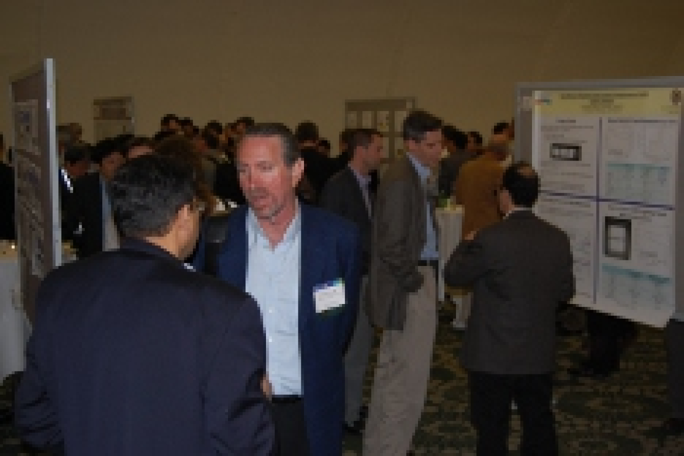 Photo of small clusters of people talking to each other in front of poster displays.