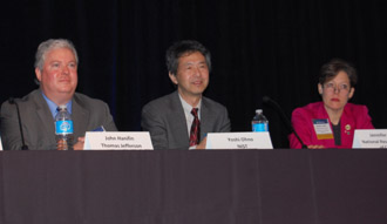 Three people in business attire seated at a table facing the audience at the conference.