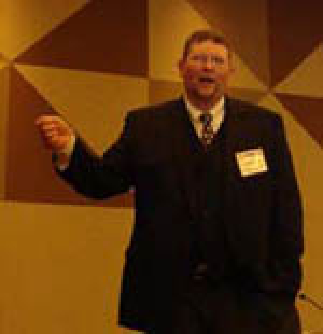 Photo of a man in a dark suit speaking.