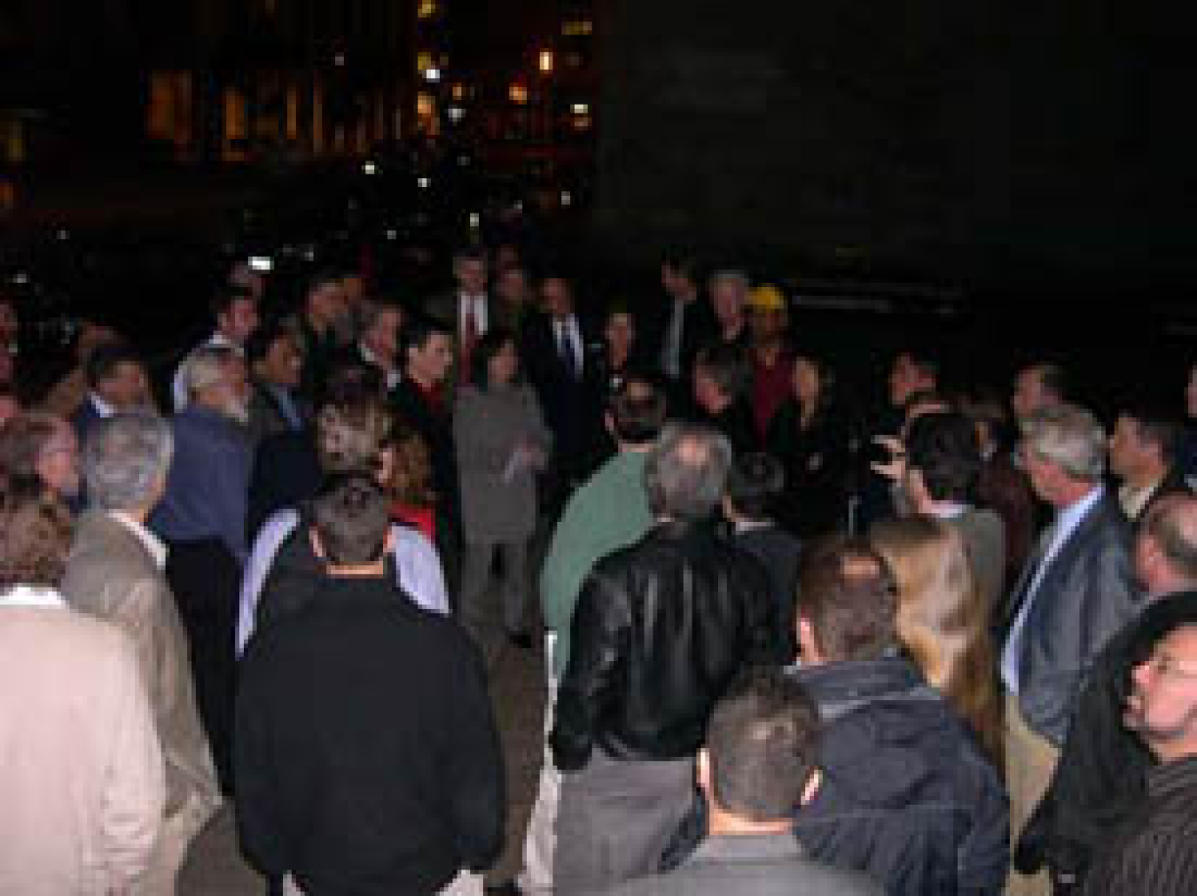 Photo of a large crowd outside at night, their backs to the camera.