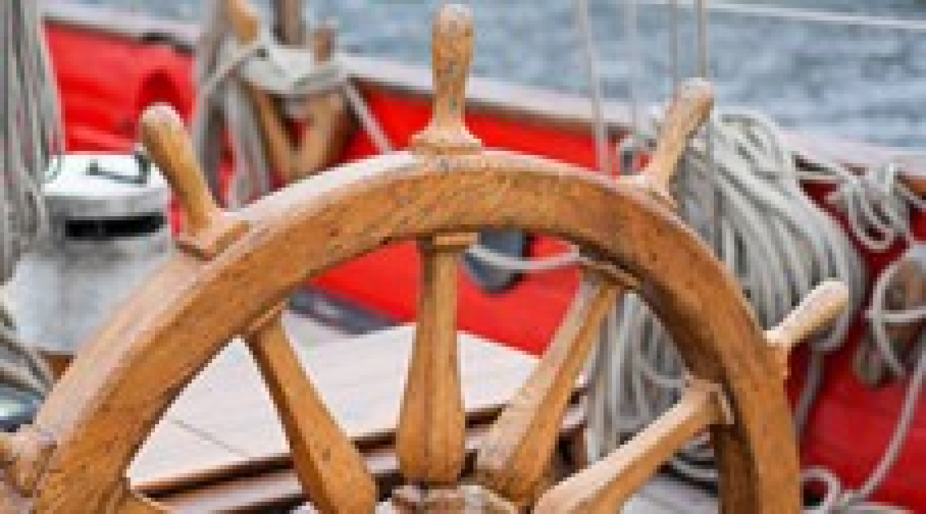 Photo of the wheel and helm of a boat.