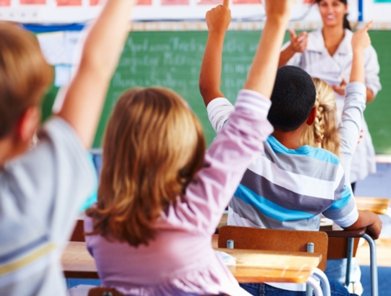 Kids' hands raised with a teacher in front of them. 