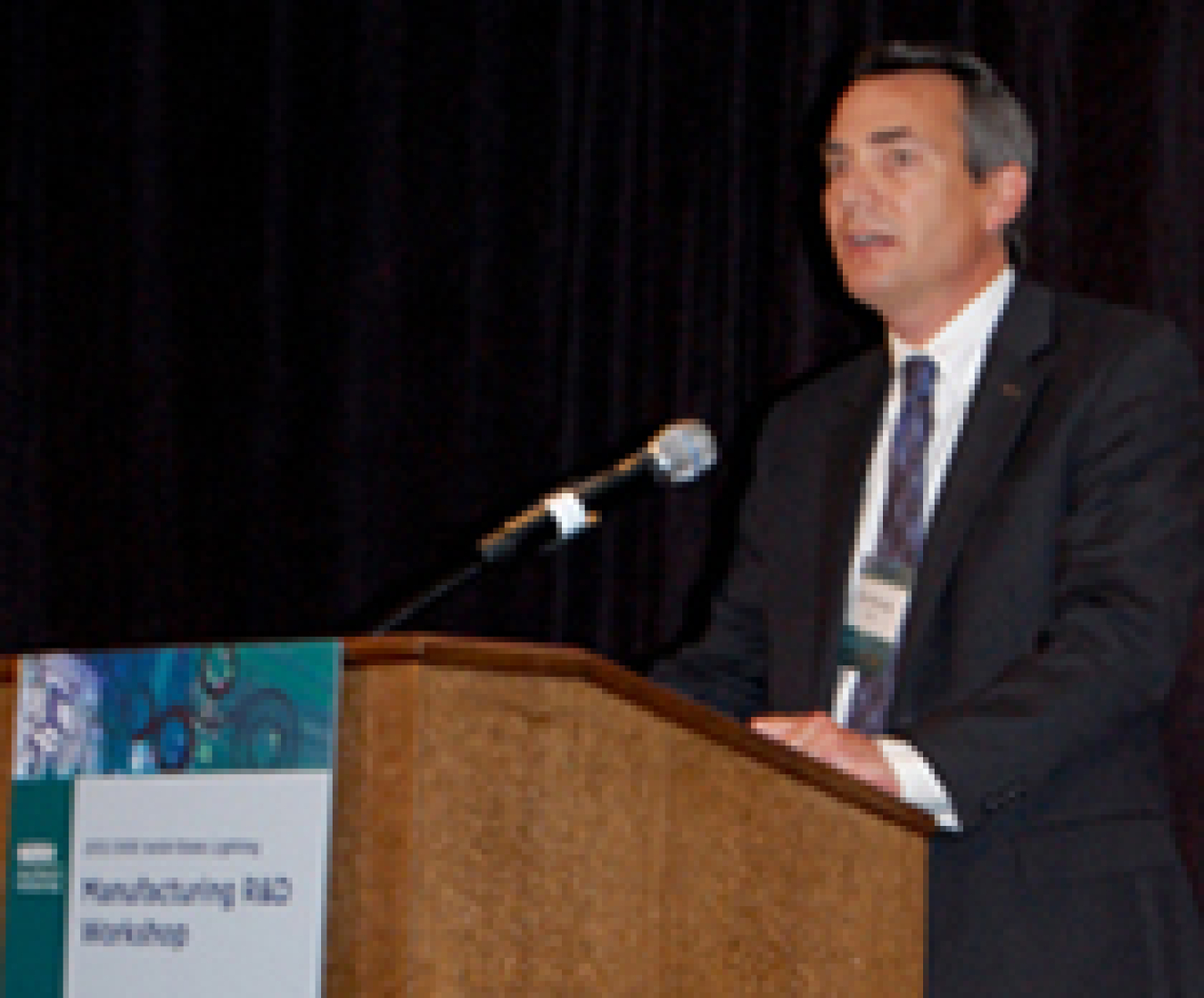 Photo of a man standing at a lectern addressing an audience.