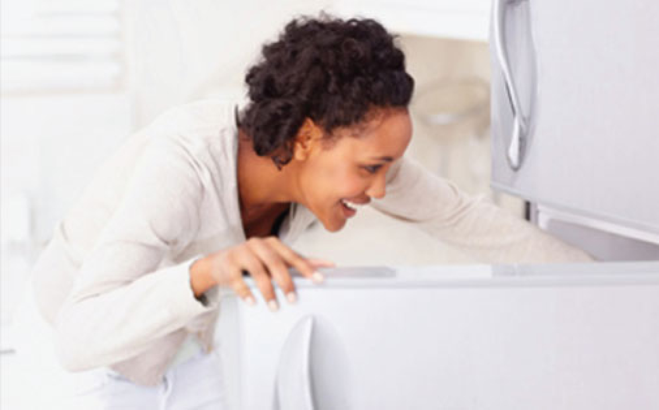 Woman reaching into a refrigerator.