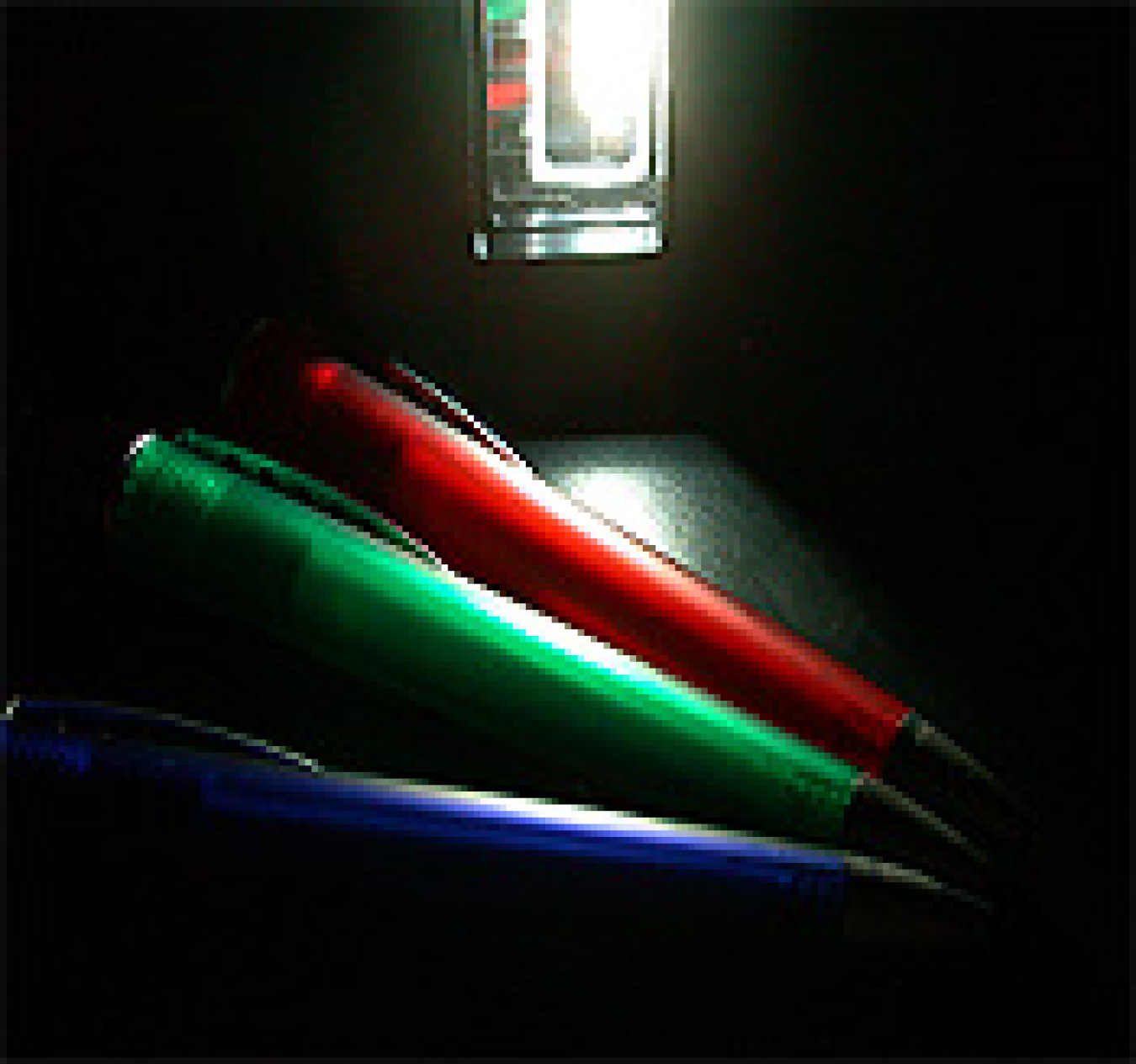 Figure 2. A 20 mm2 20 lm/W phosphorescent WOLED illuminating a red, a green and a blue pen.