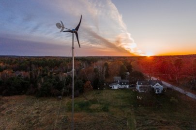 Distributed wind turbine overlooking a home at sunrise.