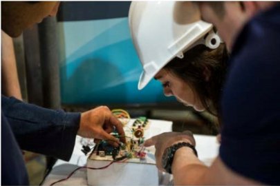Students inspect wiring and electrical components on the small wind turbine they designed and built for the DOE Collegiate Wind Competition.