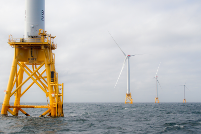 Photo of 4 wind turbines on orange platforms in the middle of ocean.