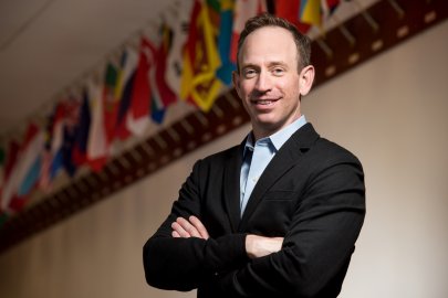 Director Douglas Mans stands in front of EMSL’s wall of flags representing its staff and users from around the world. 