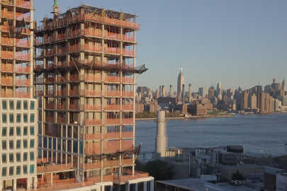 The skyline of New York City in daytime in the background, with a tall building complex under construction in the foreground. Image from ORNL.gov.