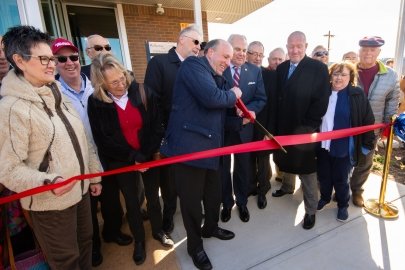 Holding an oversized pair of scissors, DOE Under Secretary for Science Paul Dabbar and Oak Ridge Mayor Warren Gooch cut a ceremonial ribbon to mark the grand opening of the K-25 History Center. 