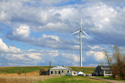 wind turbine on farmland against a cloudy but blue sky.