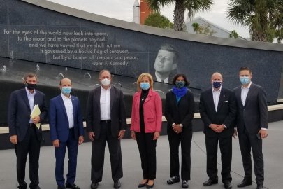 Energy leaders stand in front of Cape Canaveral. 