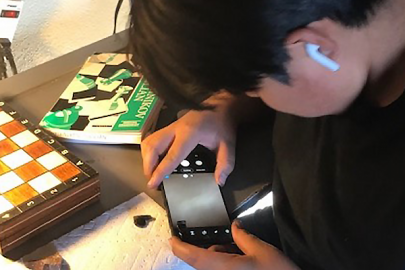  student studies a rock using a smartphone microscope.