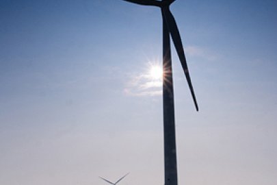 Offshore wind turbines at sea with sun shining.