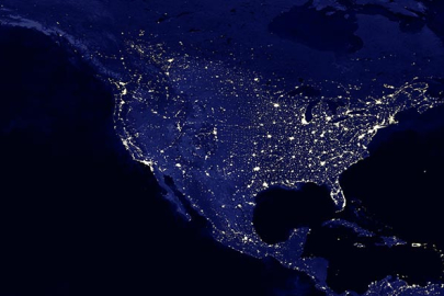 Earth at night with city lights illuminating cities in North America.