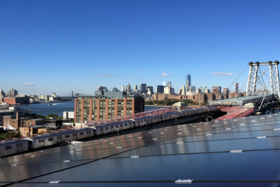 Photo of a solar array overlooking a city with train, bridges, and buildings