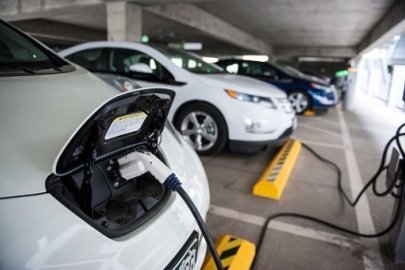 Photo of electric vehicle plugged into a charging station in parking garage