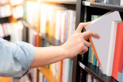 View of the arm of a person putting a book on a bookshelf.