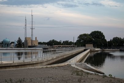 A dam on a calm canal situated in an industrial setting.