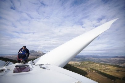 Worker sits on top of a wind turbine.