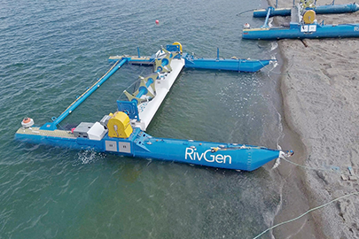 Aerial photo of two tidal turbines on the bank of a river.