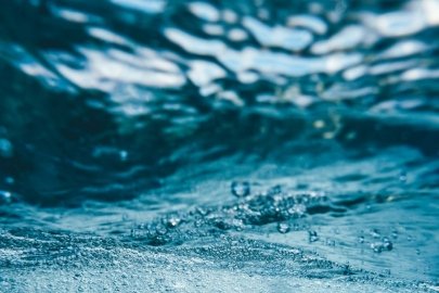 A drop of water splashes above the surface of a larger body of water.