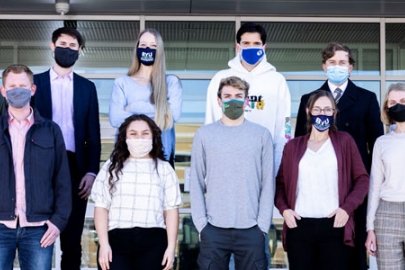 Students in masks standing in two rows on tiered bleachers.