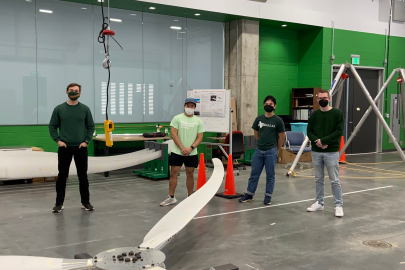 Team members of the University of Texas at Dallas collegiate wind competition stand around model wind turbines.